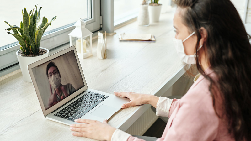 woman at laptop on teams call with someone wearing face mask
