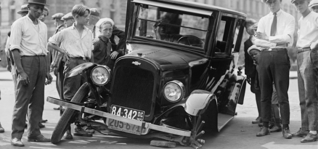 old picture of a car with one of the wheels fallen off