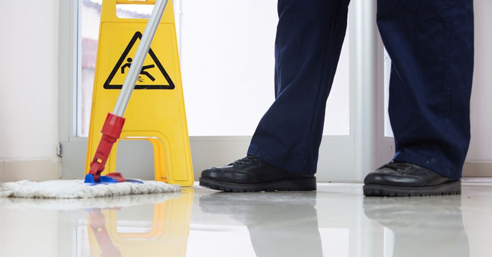 man mopping floor in hospital with wet floor sign