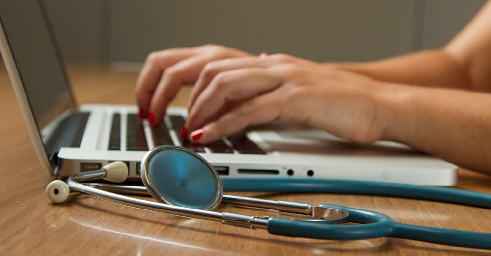 doctor working at laptop making notes