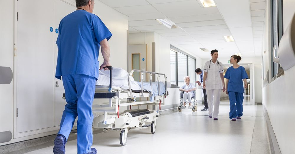 hospital corridor with nurses and patients in hospital beds