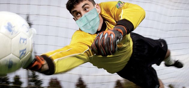 goalkeeper diving for ball with face mask on