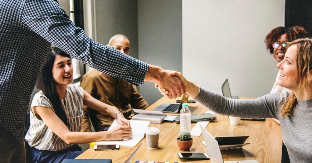 healthcare professionals around a table shaking hands with laptops