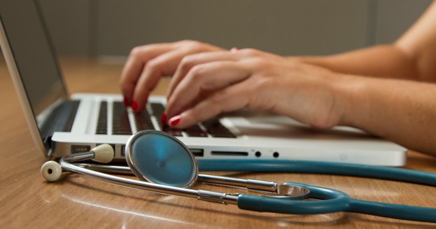 doctor working at laptop making notes